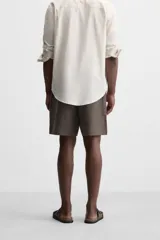 Bermuda regular fit negra confeccionada en tejido de lino. Cintura elástica ajustable con cordón y pliegues frontales. Bolsillos frontales y detalle de bolsillos traseros de plastrón.