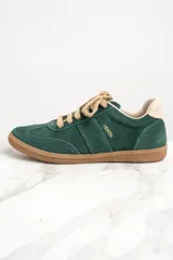 Zapatillas bajas color verde oscuro de gamuza con cordones color beige y suela de goma color marrón.