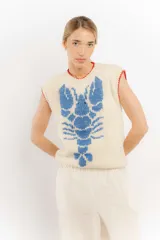 Chaleco tejido color crema con diseño de langosta azul y detalles en rojo en cuello y ruedo.