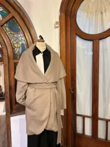 Chaquetón color beige con solapa ancha, lazo y bolsillos laterales.