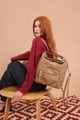 Cartera mochila color tostado, símil cuero, con compartimiento principal amplio y bolsillos frontales con cierre. Tiene correas ajustables para usar como mochila y asa superior para llevar al hombro.