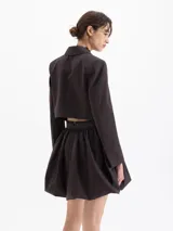 Saco blazer cropped color marrón con rayas finas, confeccionado en lanita. Presenta solapa en pico profunda, hombreras y cierre frontal con dos botones dorados.