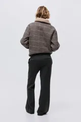 Pantalón sastrero de corte acampanado, con cierre frontal, botón oculto y corchetes. Presenta bolsillos al bies, bolsillos traseros ribeteados y pliegues marcados tanto en la parte delantera como en la trasera.