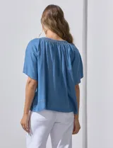 Blusa celeste de lyocell con escote en V, punto smock y lazo de ajuste.