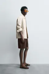 Bermuda de algodón color marrón oscuro, de corte regular fit, con cintura elástica ajustable mediante cordón. Presenta bolsillos laterales y un bolsillo trasero de vivo.