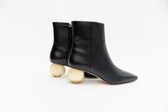 Bota de cuero color camel con punta cuadrada y cierre lateral. Tiene un taco bajo con forma de esfera dorada.