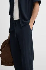 Pantalón azul marino de corte relaxed fit, confeccionado en tejido con mezcla de algodón. Presenta cintura elástica ajustable con cordón, bolsillos frontales y detalle de bolsillo trasero de plastrón.