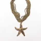Collar dorado con múltiples hilos de cuentas pequeñas y dije grande de estrella de mar texturizada.
