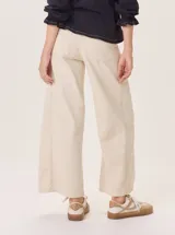 Pantalón ancho color beige claro, con corte holgado y costuras visibles en el frente de cada pierna.