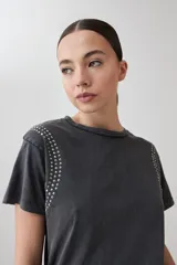 Remera rosa pastel de manga corta con tachas plateadas en los hombros.