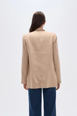 Blazer color beige, de corte holgado, con solapas anchas y bolsillos frontales.