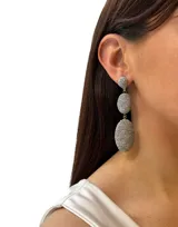 Aros colgantes largos con tres esferas de hilos dorados brillantes.