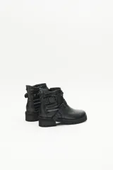 Bota de cuero negra con caña media, tiras cruzadas con hebillas y remaches metálicos, laterales matelaseados y cierre lateral interno.