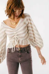 Blusa blanca de lino con escote en V, mangas largas abullonadas y frunce central.
