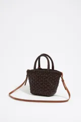 Bolso tipo tote de mimbre color marrón oscuro, con doble asa corta y correa de cuero marrón. Incluye dije circular dorado con letras grabadas.