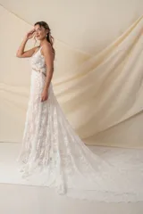 Vestido de novia largo de encaje color marfil con fondo de tul color nude, escote en V y cola de encaje con terminación de blonda.