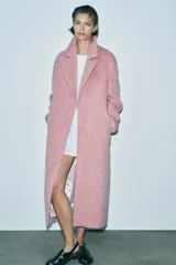 Abrigo amplio color rosa, confeccionado en hilatura con lana y alpaca. Tiene cuello solapa, manga larga, forro interior y cierre frontal con gancho metálico.