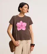 Remera marrón de algodón con estampa de una flor rosa en el frente.