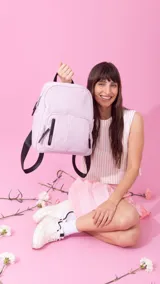 Mochila de nylon color lila con detalles en negro. Tiene un compartimento principal con cierre, dos bolsillos frontales con cierre y correas ajustables.