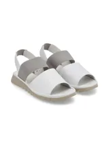 Sandalias bajas color dorado con dos tiras anchas, una sobre los dedos y otra elástica en el talón.