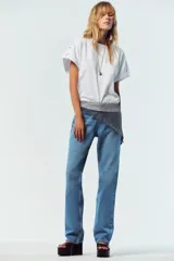 Camiseta blanca de algodón con cuello redondo y mangas cortas con vuelta, trabilla y botón.