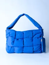 Bolso acolchado color azul con asas largas y cierre lateral.