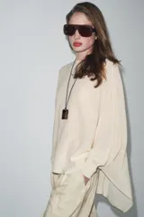 Sweater color crema de tejido de punto liso, con cuello barco y mangas anchas que se estrechan hacia la muñeca.