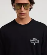 Remera negra de corte relajado con cuello redondo y manga corta. Presenta un pequeño estampado blanco en el pecho izquierdo con el texto "DEEP THOUGHTS" y un símbolo debajo.