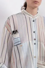 Camisa de manga larga con cuello mao, botones en el frente, fit holgado y dos bolsillos en la delantera.