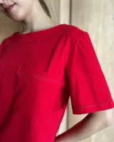 Remera negra con cuello redondo y mangas cortas, con detalle de pespuntes blancos en cuello, mangas, bolsillos frontales y ruedo.