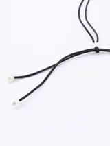Gargantilla choker de cordón negro con dos perlas blancas en los extremos.