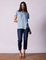 Camisa celeste de tencel con cuello con solapa, escote en V y abertura central con botones. Delantera con detalle en punto smock.