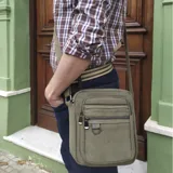 Morral bandolera rectangular color verde militar, confeccionado en tela canvas. Tiene correa de galón regulable, cierre superior, dos bolsillos frontales con cierre, bolsillo trasero con cierre y bolsillos internos.
