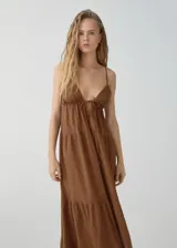 Vestido largo color marrón, con escote de pico y tirantes finos. Presenta un corte evasé y detalles fruncidos. El escote tiene un cierre de lazo.