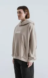 Buzo con capucha color beige, con costuras expuestas, calce oversize crop y la palabra "AMOR" estampada en el pecho.