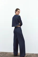 Pantalón de tiro alto color azul denim, con pinzas delanteras, bolsillos frontales, pernera ancha y pespuntes combinados a contraste en color beige.