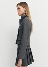Blazer gris con diseño crop, corte recto, cuello con solapa de muesca, manga larga con aberturas en los puños, bolsillo de parche en el pecho, dos bolsillos delanteros de ribete y solapa, cierre delantero con botones y forro interior.