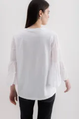 Blusa blanca de algodón con mangas largas abullonadas de gasa y puños elásticos.