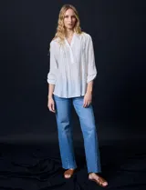 Blusa blanca de gasa bambula, marca Zac & Rachel. Cuello a la base, escote en V con apertura y botones. Largo de manga regulable con presilla y botón.