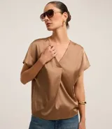 Blusa color café confeccionada en poliéster y elastano, con acabado satinado, escote V y mangas cortas. Presenta pliegues delanteros.