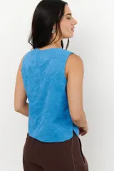 Top color crema con bordado floral, sin mangas, con cuello redondo y cierre frontal con botones.