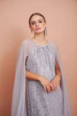 Vestido largo de fiesta color plata con encaje y brillos, cuello halter y capa de gasa larga.