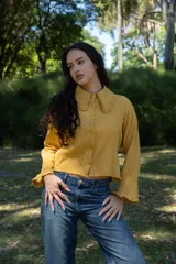 Camisa color mostaza de muselina, corte amplio, cuello con volados y botones frontales.