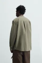Camisa color beige claro de lino y algodón, corte relaxed fit, cuello mao, manga larga con puños abotonados y cierre frontal con botones. Marca Zara.