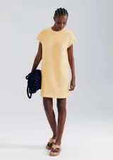 Vestido corto color crema, de corte recto y mangas cortas con bolsillo en el pecho.