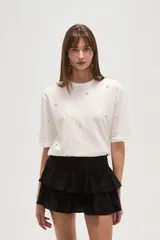 Remera blanca de algodón con tachas plateadas y cuello redondo.