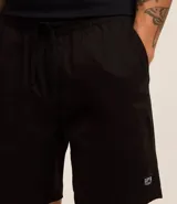 Bermuda de sarga lavada color verde claro, con lazo ajustable en la cintura, bolsillos laterales y un pequeño parche negro con logo en la pierna izquierda.