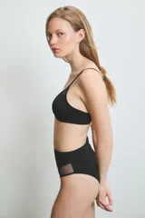 Conjunto de lencería color piel, compuesto por un corpiño triangular con breteles finos y detalle de tul en el escote, y una bombacha vedetina alta con detalle de tul en los laterales.