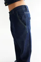 Pantalón de jean azul oscuro, de corte baggy y tiro bajo, con pespuntes a contratono color verde lima y logo bordado en el bolsillo trasero. Confeccionado en denim 100% algodón.