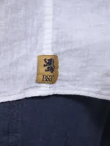 Camisa blanca de lino con cuello mao, manga larga con puños abotonados y bolsillo en el pecho.